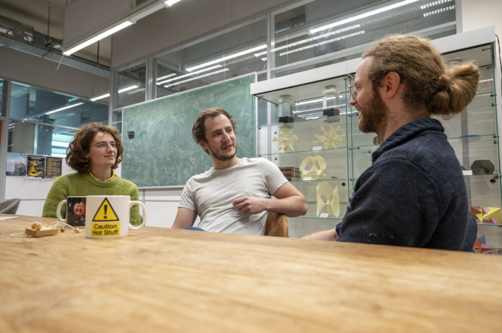 Drie veiligheidsprofessionals in gesprek aan een tafel op een onderwijsinstelling